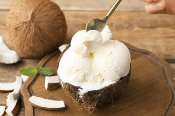 Coconut with tasty ice cream on wooden background