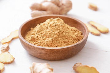 Bowl with ginger powder on light wooden background