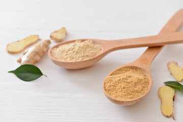 Spoons with ginger powder on light wooden background, closeup