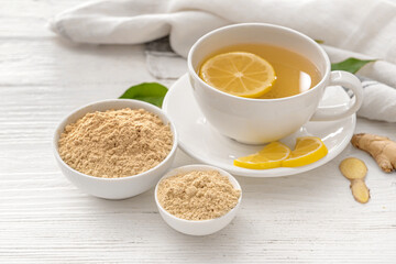 Composition with cup of ginger tea and powder on light wooden background