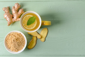 Cup of ginger tea and powder on color wooden background