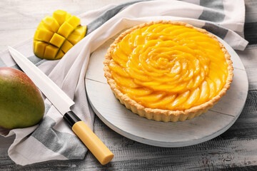 Board with tasty mango pie on wooden background