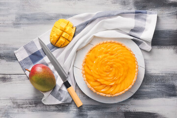 Board with tasty mango pie on wooden background