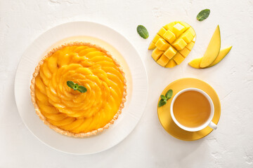 Plate with tasty mango pie and cup of tea on light background