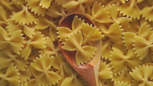 Wooden spoon with farfalle pasta rotates in a circle