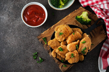 Homemade chicken nuggets with vegetables on a wooden board, top view