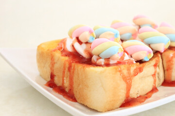 Close-up Pastel Colored Marshmallows on a slice of Bread topped with strawberry sauce.