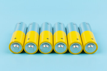 Photo of gray-yellow alkaline AA batteries on blue background. Recycling of rechargeable NiMH...