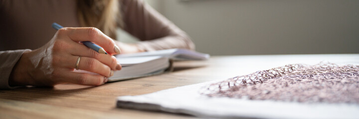 Wide view image of a woman writing in notebook