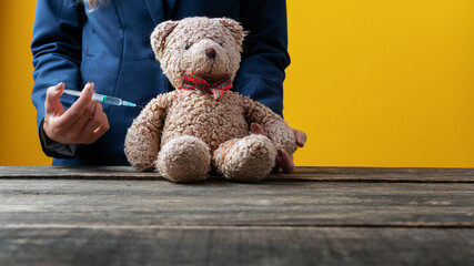 Closeup of a medical doctor vaccinating a teddy bear