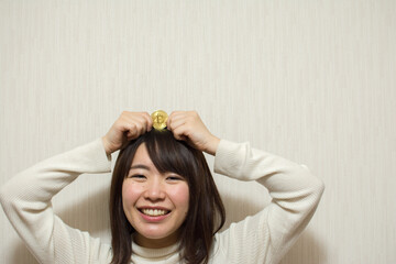 A young woman holds a bitcoin on her head.