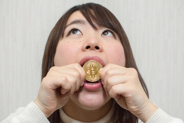 A young woman tries to eat bitcoins. She got Bitcoin by trading cryptocurrencies.