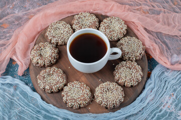 Sesame caramel cookies on a wooden board with a cup of tea