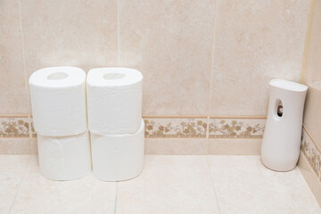 Rolls of white toilet paper and air freshener on the toilet shelf. Modern electric air freshener.