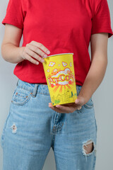 Young girl in red shirt holding a box of popcorns