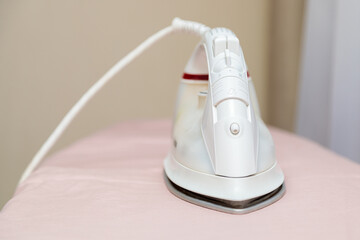 Iron on ironing board with pink linens. Close-up