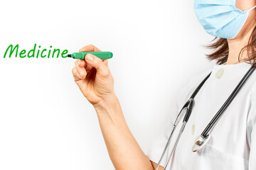 Doctor with mask writing the word medicine with a marker pen green