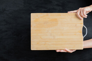 Holding a square wooden board on black background