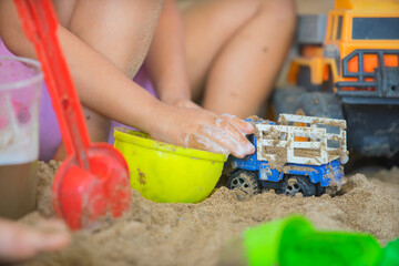 Little boy playing with children truck in the sandpit.