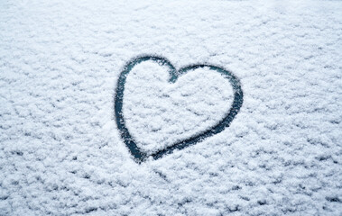 snow background with frozen heart on the glass