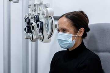 Young patient eye examination at optometrist using phoropter