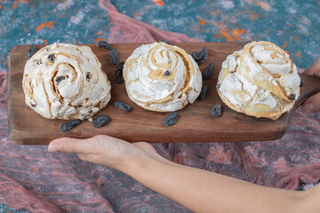 Fried meringue cookie with black raisines on a wooden board