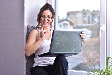 Caucasian brunette woman at window sit with laptop