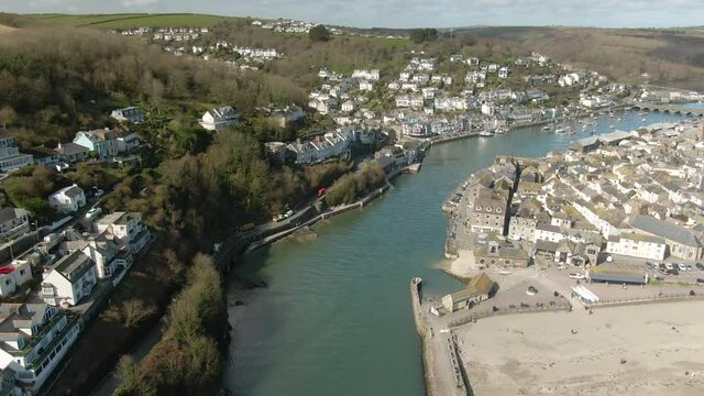 Aerial of Looe estuary at the mouth looking inland. Lifeboat station and pier in the foreground