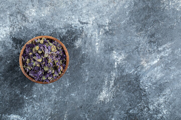 Obraz na płótnie Canvas Dried purple flowers in wooden bowl