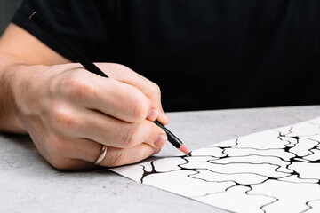 Man is drawing an abstract imaginary picture of curves by a black pencil in his hand. A...