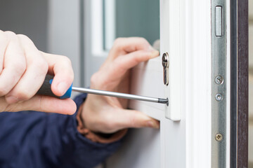 Handyman installing door lock in front door. Checking the door lock with a screwdriver for...