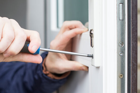Handyman installing door lock in front door. Checking the door lock with a screwdriver for operability.