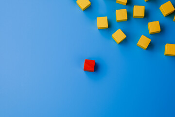 Red wooden block standing out on blue background. Leadership and innovation concept