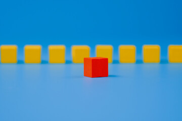 Red wooden block standing out on blue background, closeup. Abstract leadership concept