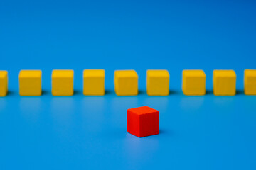 Red wooden block standing out on blue background. Abstract leadership concept