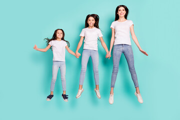 Fototapeta premium Full length body size photo funky cool sisters jumping up wearing jeans white t-shirts isolated vibrant blue color background