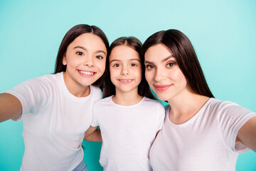 Photo portrait of sisters smiling happy taking selfie wearing white t-shirts isolated vivid blue color background
