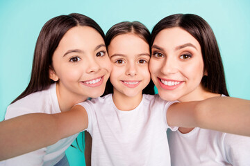 Photo portrait of three cheerful sisters smiling taking selfie isolated on bright blue color background