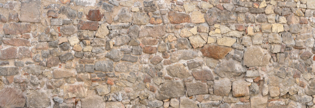 Panorama - Alte grau braune Mauer aus vielen unterschiedlichen Natursteinen in unregelm&auml;&szlig;iger Anordnung 