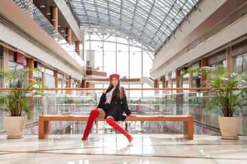 Fashion model advertising fashion store or shopping center. Stylish brunette poses professionally for camera in place of boutiques. Concept of consumerism, sale, shopaholism. Copy space for site