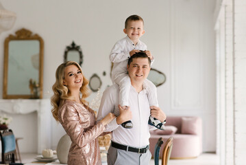 Beautiful young family man woman and son in smart clothes in a luxurious bright interior, happy family
