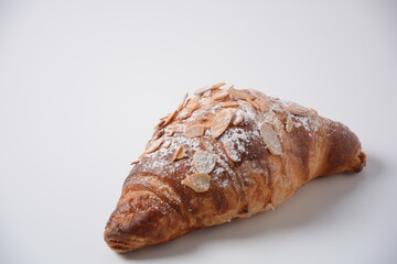 Traditional French breakfast croissant with almonds on white background