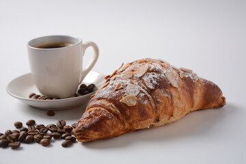 Fresh croissant with a cup of coffee, roasted beans on vintage background