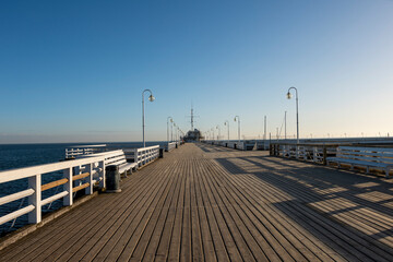 Poranek na molo. Drewniane, długie molo o świcie w bezchmurny dzień. Widok na Morze Bałtyckie