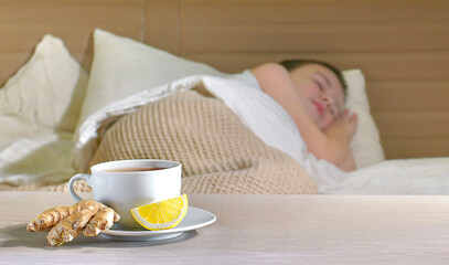 A cup of tea on a saucer with ginger root and a slice of lemon on a blurred background. Sleeping...