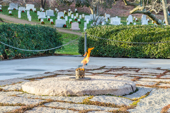 Eternal Fire at President J.F. Kennedy Grave Site in Arlington National Cemetery, Washington DC, USA. Soldier Gravestones in Background	