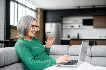 Video call concept, lovely elderly woman with nice wrinkles, narrow lips, smiling, chatting with...