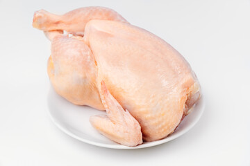 carcass of raw chicken on a white plate on a white background. 