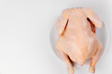 carcass of raw chicken on a white plate on a white background. 