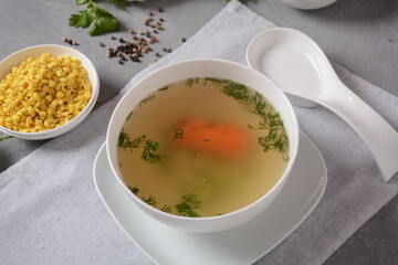 Chicken soup , chicken broth, with pieces of chicken and vegetables and shkedei marak an Israeli food product crisp mini croutons used as a soup accompaniment